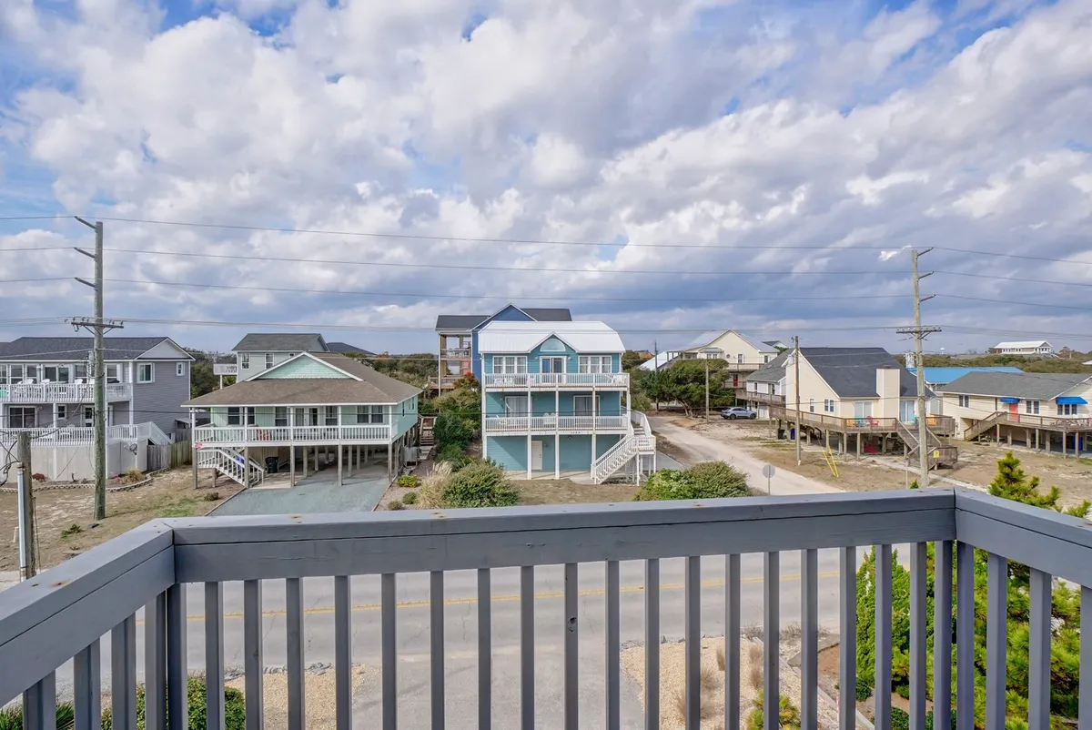 A wide-angle view of the local neighborhood, showcasing nearby houses, the road, and a cloudy sky. The scene evokes the experience of strolling through the area and exploring the local community.